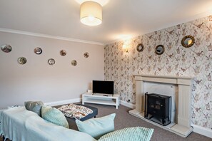 A living room with a fireplace, a television, and a sofa with cushions.