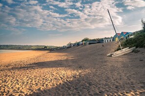 Ein Strand mit einer Reihe bunter Strandhäuser und einem Segelboot im Sand.