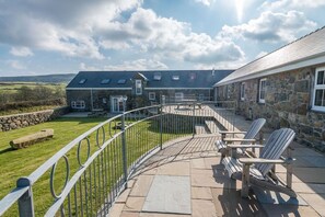 A stone building with a patio area, outdoor seating, and a view of the surrounding landscape. - Large 4 Bedroom Holiday Cottage on the Llŷn Peninsula | Deri-Sarn (Pwllheli)