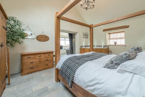A bedroom with a four-poster bed, wooden dresser, and a large mirror. - Large 4 Bedroom Holiday Cottage on the Llŷn Peninsula | Deri-Sarn (Pwllheli)