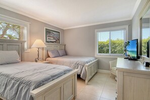 Un dormitorio con dos camas, televisión y ventana con persianas.