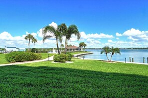A waterfront property with a swimming pool, palm trees, and a clear blue sky. - Sunrise Cove 108: Ground floor Waterfront Condo on Siesta Key w/ Sleeper Sofa (Sarasota)