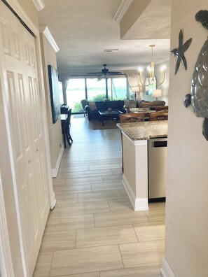 A spacious kitchen with a large island, a dining area with a view, and a hallway leading to a door. - Sunrise Cove 110: Ground Floor Waterfront Condo on Siesta Key w/ Washer/Dryer (Sarasota)