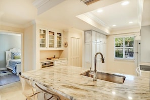 A modern kitchen with a marble countertop, stainless steel sink, and white cabinetry. - Sunrise Cove 118: Remodeled Waterfront Condo on Siesta Key w/ Sleeper Sofa (Sarasota)