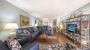 A living room with a sofa, coffee table, and TV stand with decorative items. - Sunrise Cove 130: Ground Floor Waterfront Condo on Siesta Key (Sarasota)