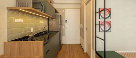 A compact kitchen with a stove, microwave, and wooden cabinets.