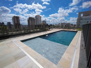 A rooftop swimming pool with a cityscape view, surrounded by a metal fence and a tiled deck. - Librio by Bhomy (São Paulo)