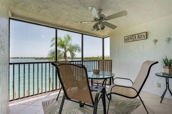 Een balkon met uitzicht op het water, een plafondventilator en een bord met de tekst 'SIESTA KEY'.