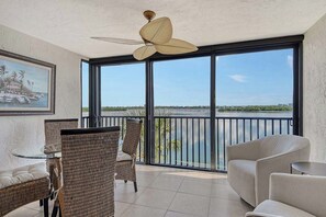 A balcony with a view of a body of water, wicker furniture, and a ceiling fan. - Sunrise Cove 230: Remodeled Waterfront Condo on Siesta Key w/ Sleeper Sofa (Sarasota)