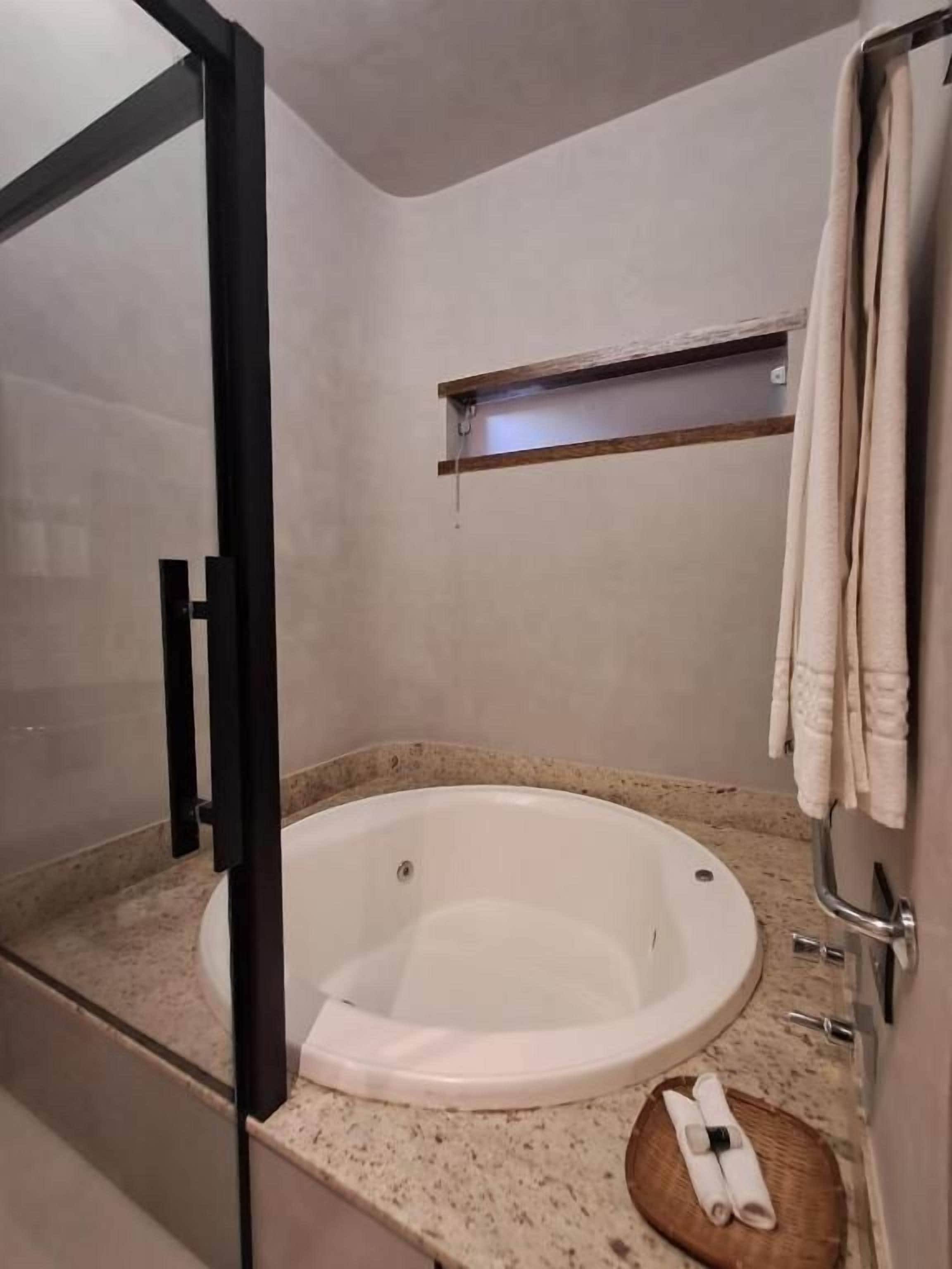Un baño con una bañera, un perchero para toallas y un taburete de madera.