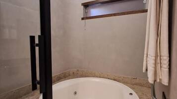 Un baño con una bañera, un perchero para toallas y un taburete de madera.