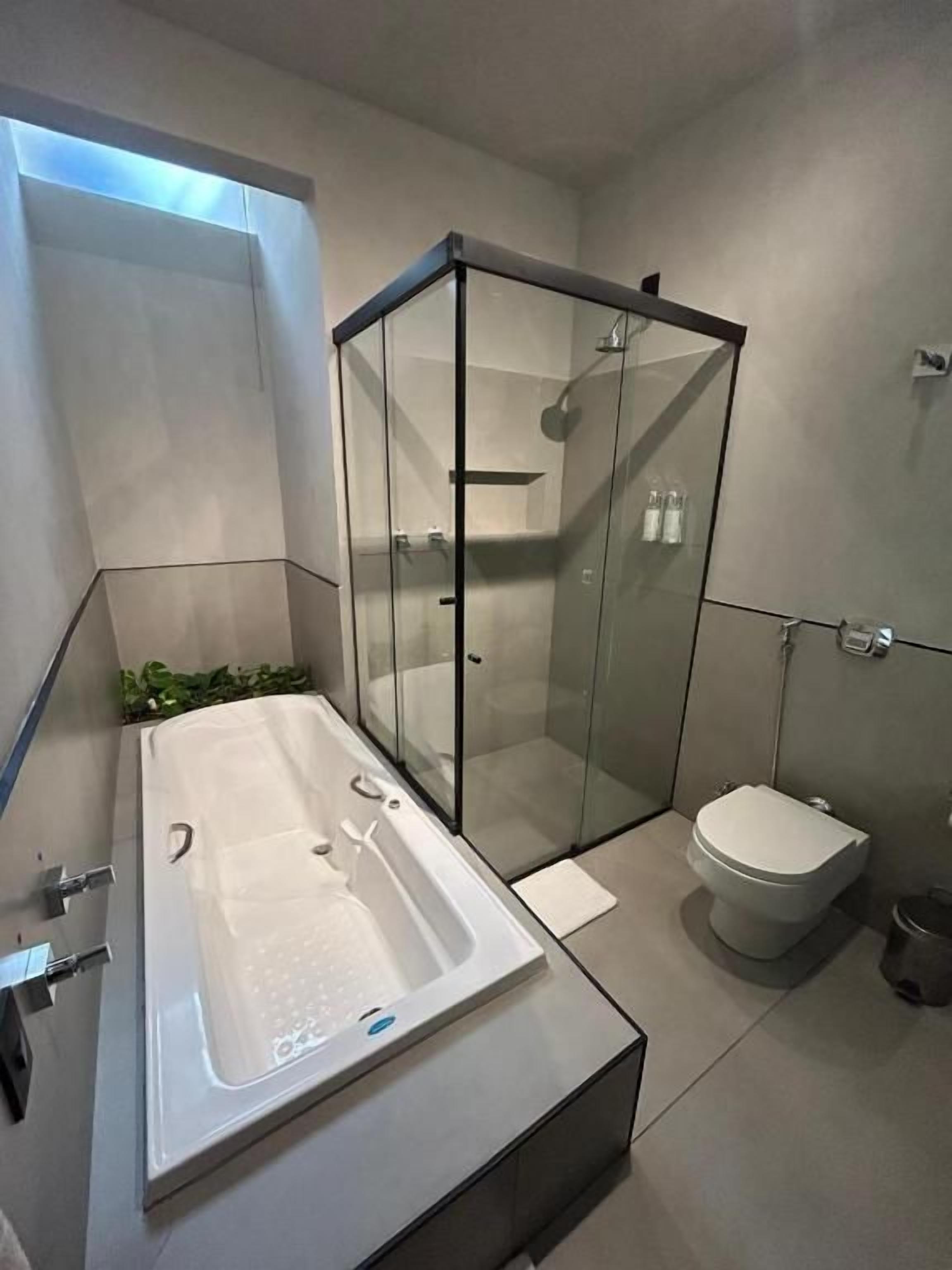 A modern bathroom with a glass-enclosed shower, a standalone bathtub, and a toilet.