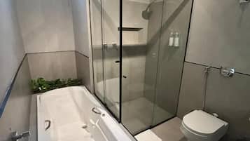 A modern bathroom with a glass-enclosed shower, a standalone bathtub, and a toilet.