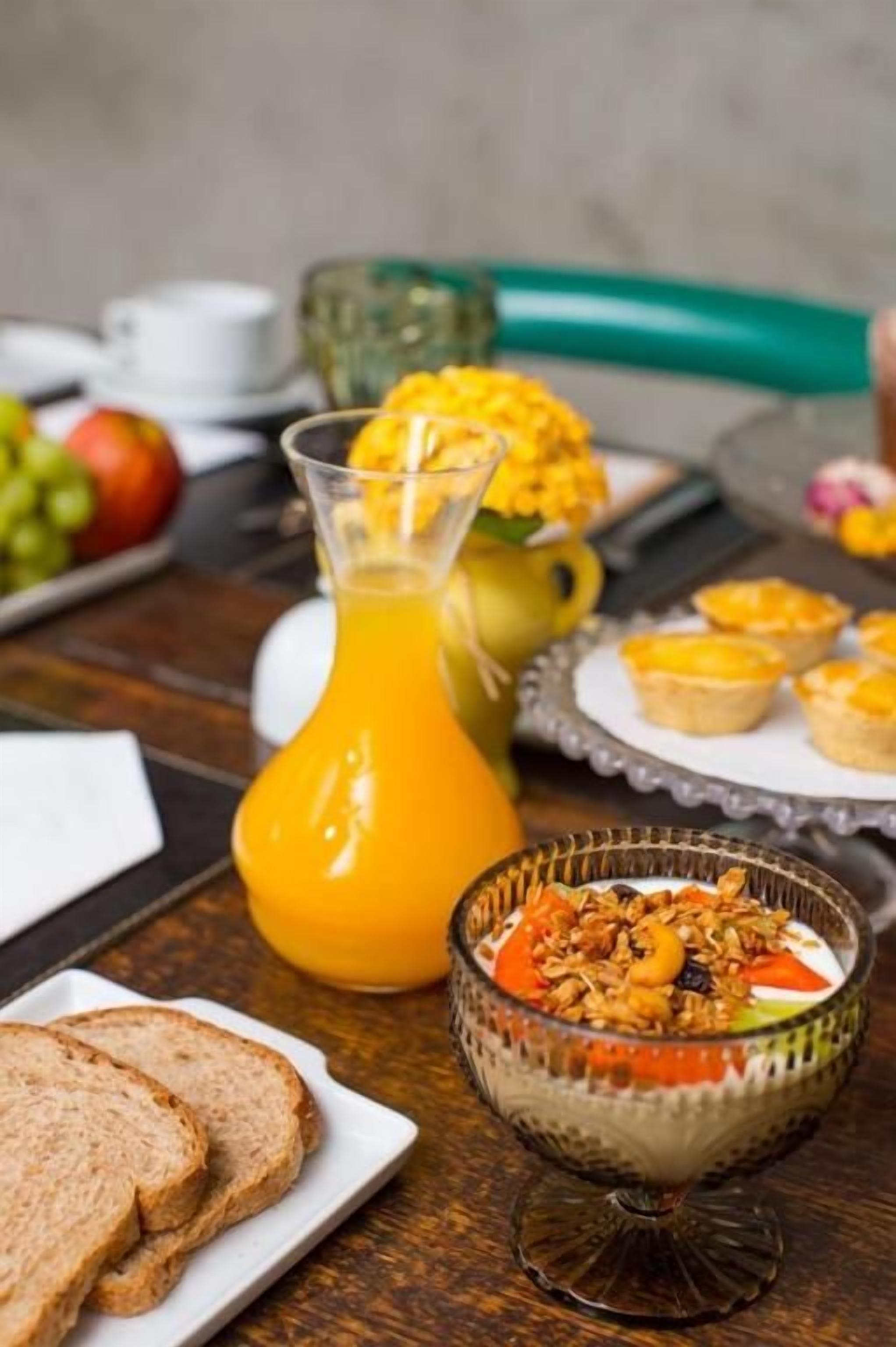 A breakfast setting with a glass of orange juice, a bowl of cereal, and a plate of toast.