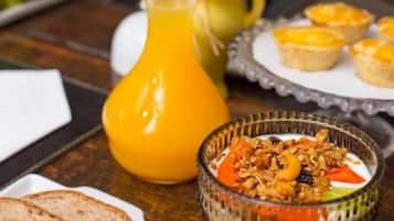 A breakfast setting with a glass of orange juice, a bowl of cereal, and a plate of toast.