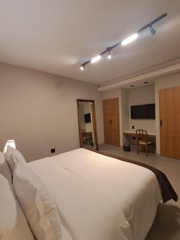 A bedroom with a bed, a desk, and a chair.