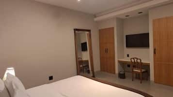 A bedroom with a bed, a desk, and a chair.