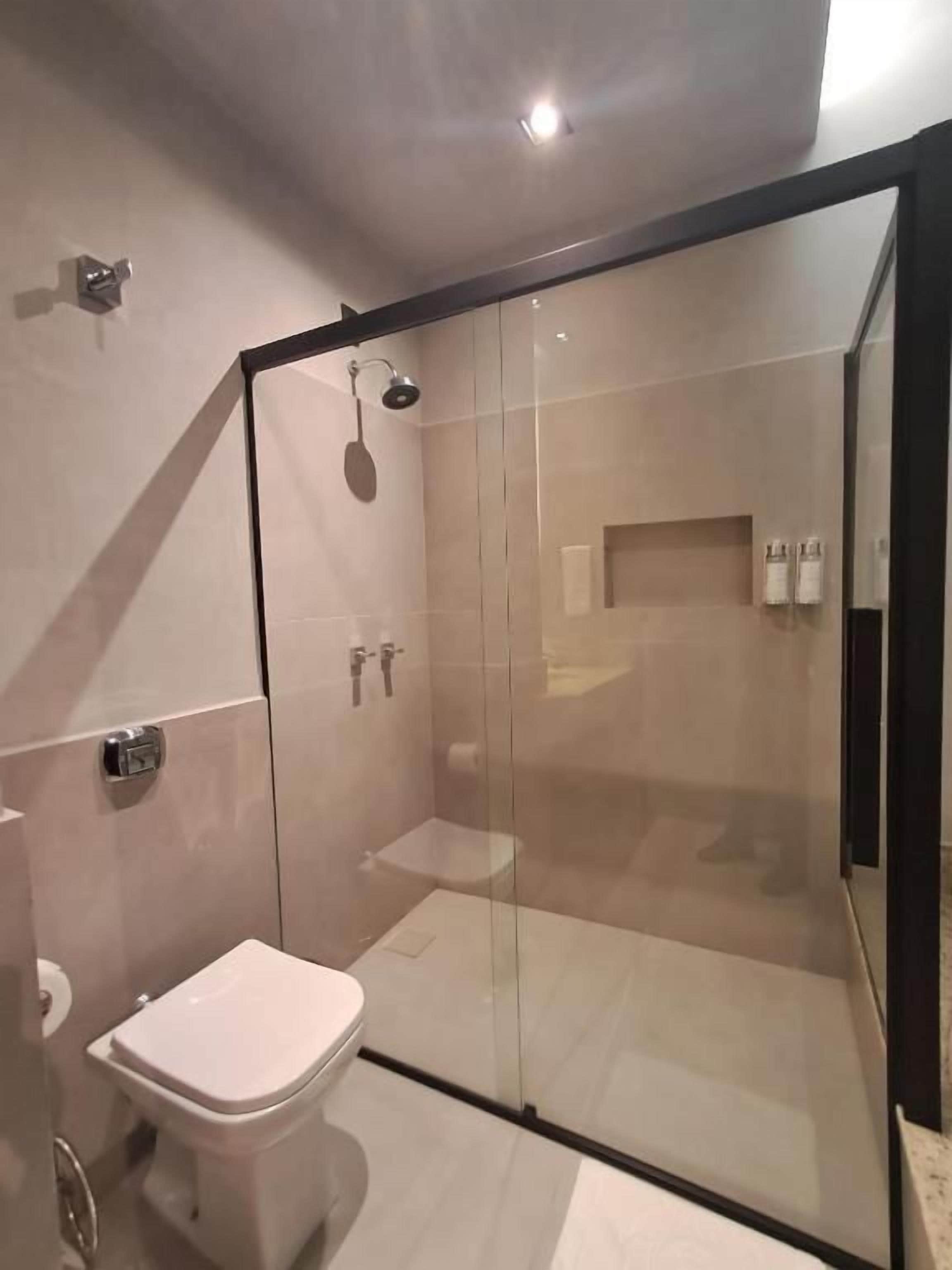 Casa de banho moderna com chuveiro de vidro, sanita e lavatório.
