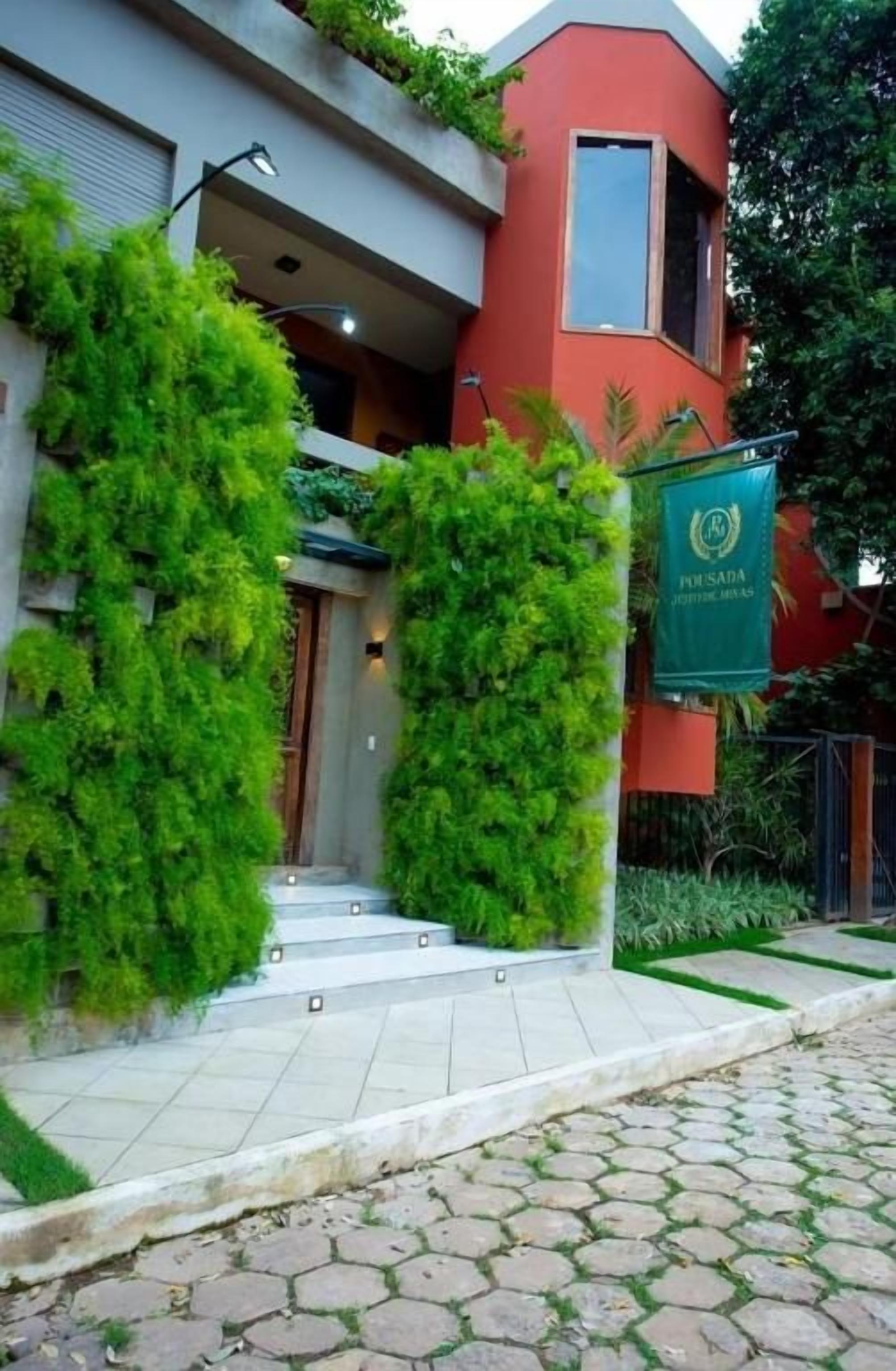 A building with a red facade, a green sign, and a staircase leading to the entrance.