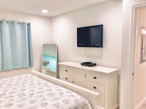 A bedroom with a bed, a dresser, a television, and a mirror. - Sunrise Cove 303: Remodeled Waterfront Condo on Siesta Key w/ 2 Sleeper Sofas (Sarasota)