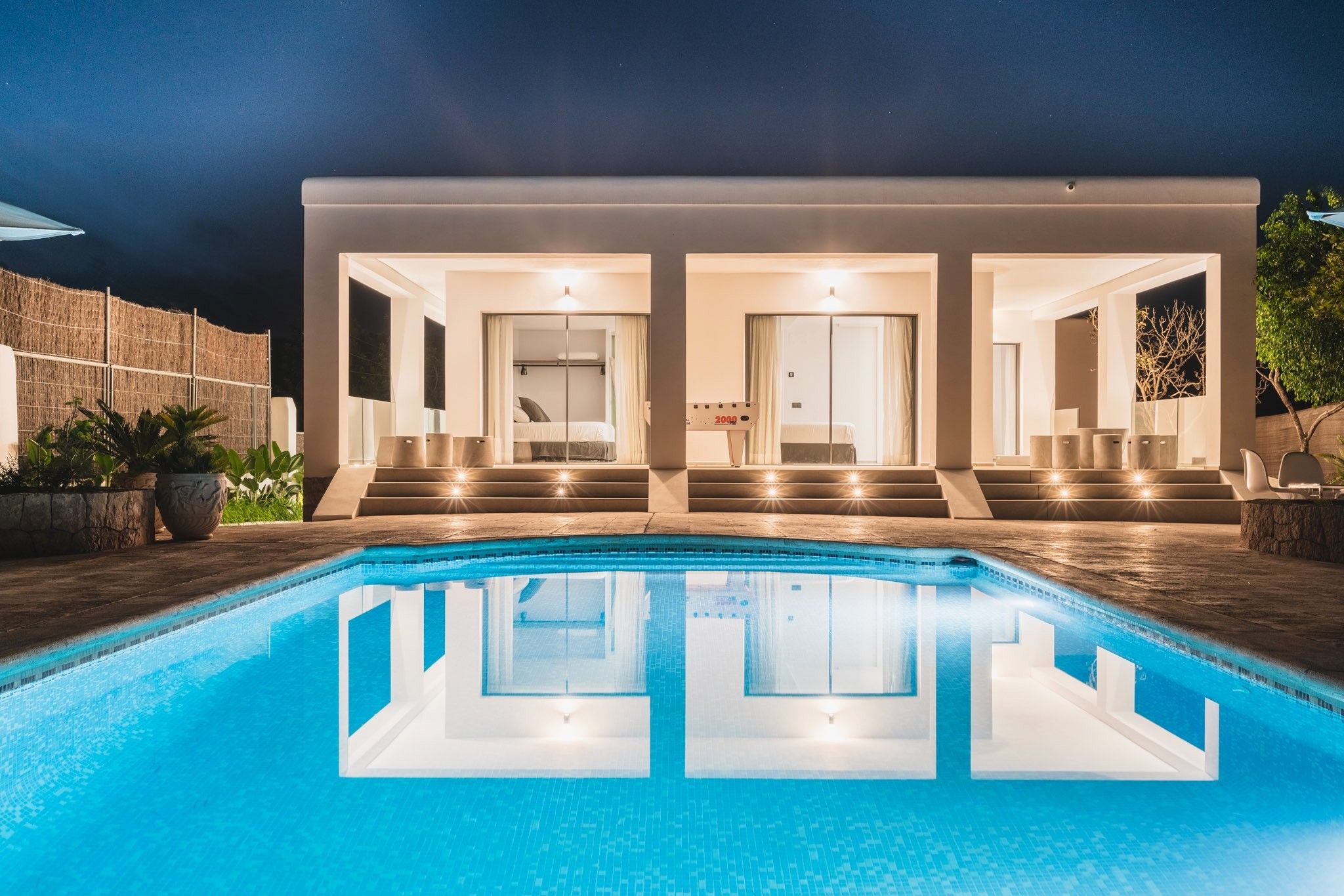 A modern house with a swimming pool, two bedrooms, and a staircase leading to the bedrooms.
