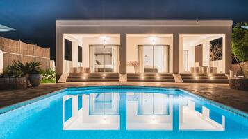 A modern house with a swimming pool, two bedrooms, and a staircase leading to the bedrooms.