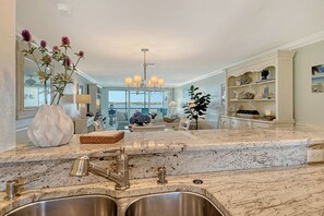 Cozinha com uma ilha grande, pia de aço inoxidável e vista para o exterior.