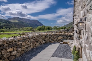 A stone wall leading to a building with a stone pathway and a mountain view in the background. - Beautiful Secluded Cottage at the Foot of Yr Wyddfa (Snowdon) | Clogwyn-Mawr (Rhyd Ddu)