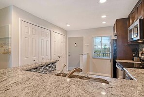 A kitchen with granite countertops, white cabinetry, and a window providing natural light. - Sunrise Cove 311: Remodeled Waterfront Condo on Siesta Key w/ Murphy Bed (Sarasota)