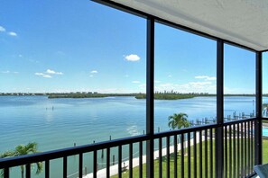 Uitzicht vanaf een balkon op kalm water, onder een heldere lucht.