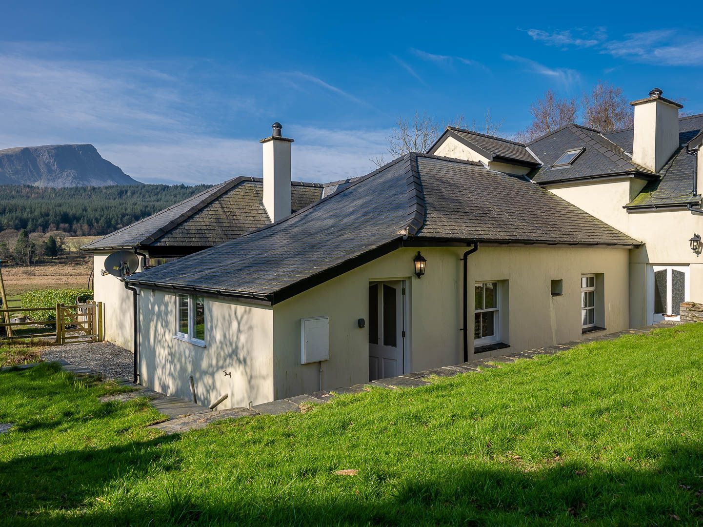 A two-story house with a sloped roof, a satellite dish, and a chimney.