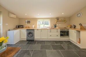 A modern kitchen with a washing machine, oven, and a window with a view of the outdoors.