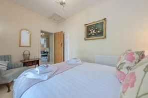 Un dormitorio con una cama, una silla, un aparador, un espejo y un cuadro en la pared.