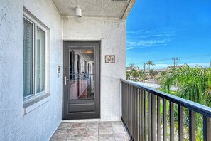 A building entrance with a black door, a window, and a balcony with a railing. - Sunrise Cove 324: Spacious Fully Remodeled Waterfront Condo on Siesta Key (Sarasota)
