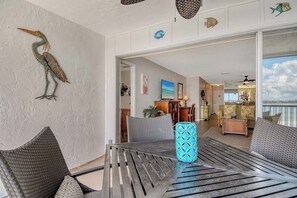 A room with a view of the sea, a dining area with a table and chairs, and a living area with a sofa and a coffee table. - Sunrise Cove 326: Remodeled Waterfront Vacation Rental Condo on Siesta Key (Sarasota)
