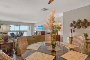 A dining area with a round table, chairs, and a vase with pampas grass. - Sunrise Cove 326: Remodeled Waterfront Vacation Rental Condo on Siesta Key (Sarasota)