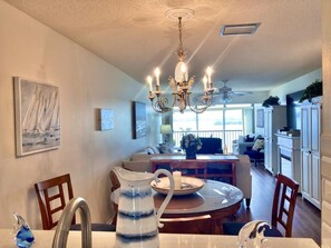 A dining area with a chandelier, a table, chairs, and a pitcher. - Sunrise Cove 327: Waterfront Cozy Cottage Condo on Siesta Key (Sarasota)