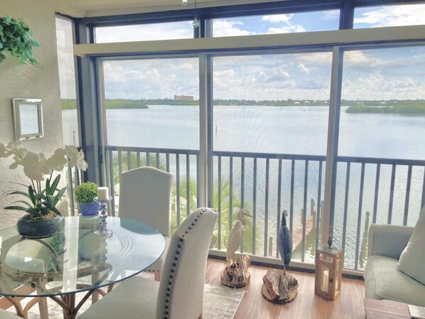 Un balcone con vista su un lago, un tavolino in vetro e sedie, e alcuni elementi decorativi.