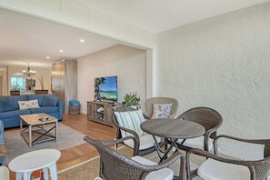 Un salon avec un canapé, une table basse et des fauteuils en osier.