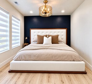 Ein modernes Schlafzimmer mit einem großen Bett, einer dunklen Akzentwand und einer Deckenleuchte.
