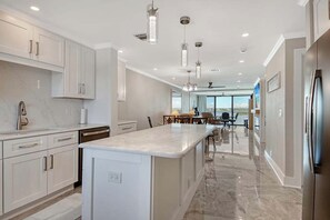 A modern kitchen with a central island, white cabinetry, and pendant lighting. - Sunrise Cove 418: Remodeled Waterfront Condo on Siesta Key w/ Sleeper Sofa (Siesta Key)