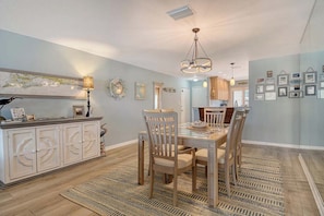 A dining area with a wooden table and chairs, a cabinet with decorative handles, and a patterned rug. - Sunrise Cove 425: Spacious Waterfront Condo on Siesta Key with Sleeper Sofa (Sarasota)