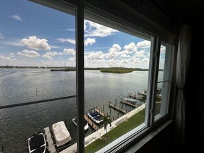 Blick aus einem Fenster auf ruhiges Wasser mit Stegen und Booten.