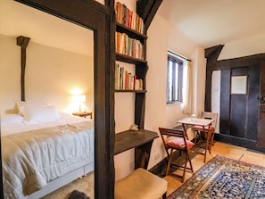 A bedroom with a bed, bedside table, lamp, bookshelf, desk, chair, and a rug. - Hole House (Seaton)