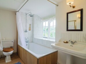 Ein Badezimmer mit einer Badewanne, einer Toilette, einem Fenster und einem Waschbecken.
