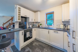 A modern kitchen with white cabinetry, a built-in oven, and a window with a blue-tinted glass.