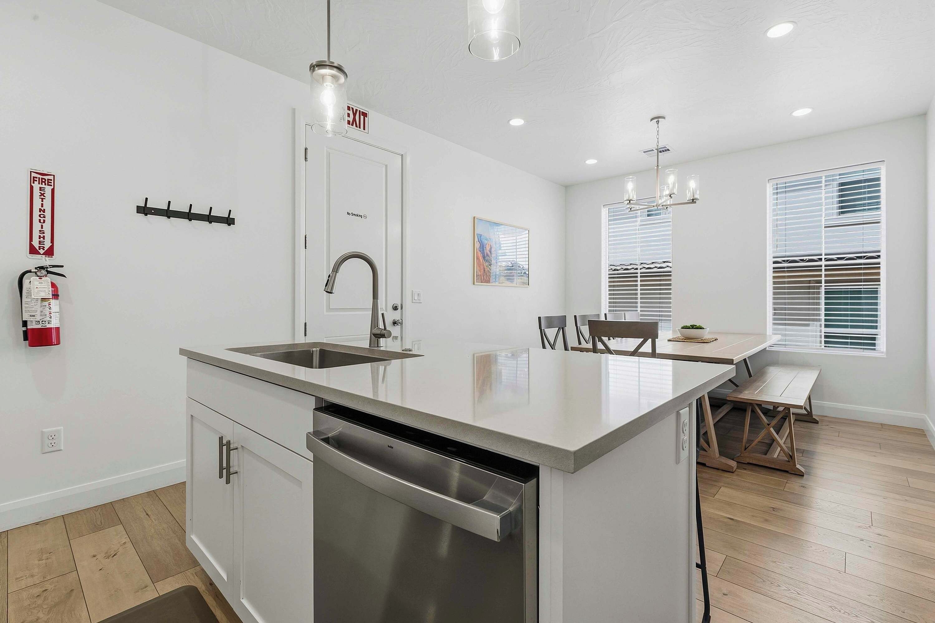 A modern kitchen with a central island, stainless steel appliances, and a dining area with a bench.