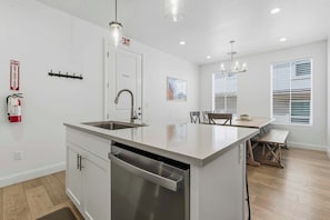 A modern kitchen with a central island, stainless steel appliances, and a dining area with a bench.