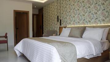Un dormitorio con una cama, cabecera de madera, pared con estampado floral y una puerta.