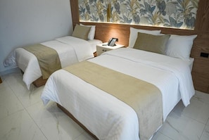 Habitación de hotel con dos camas, una mesita de noche con teléfono y un diseño de papel tapiz floral.